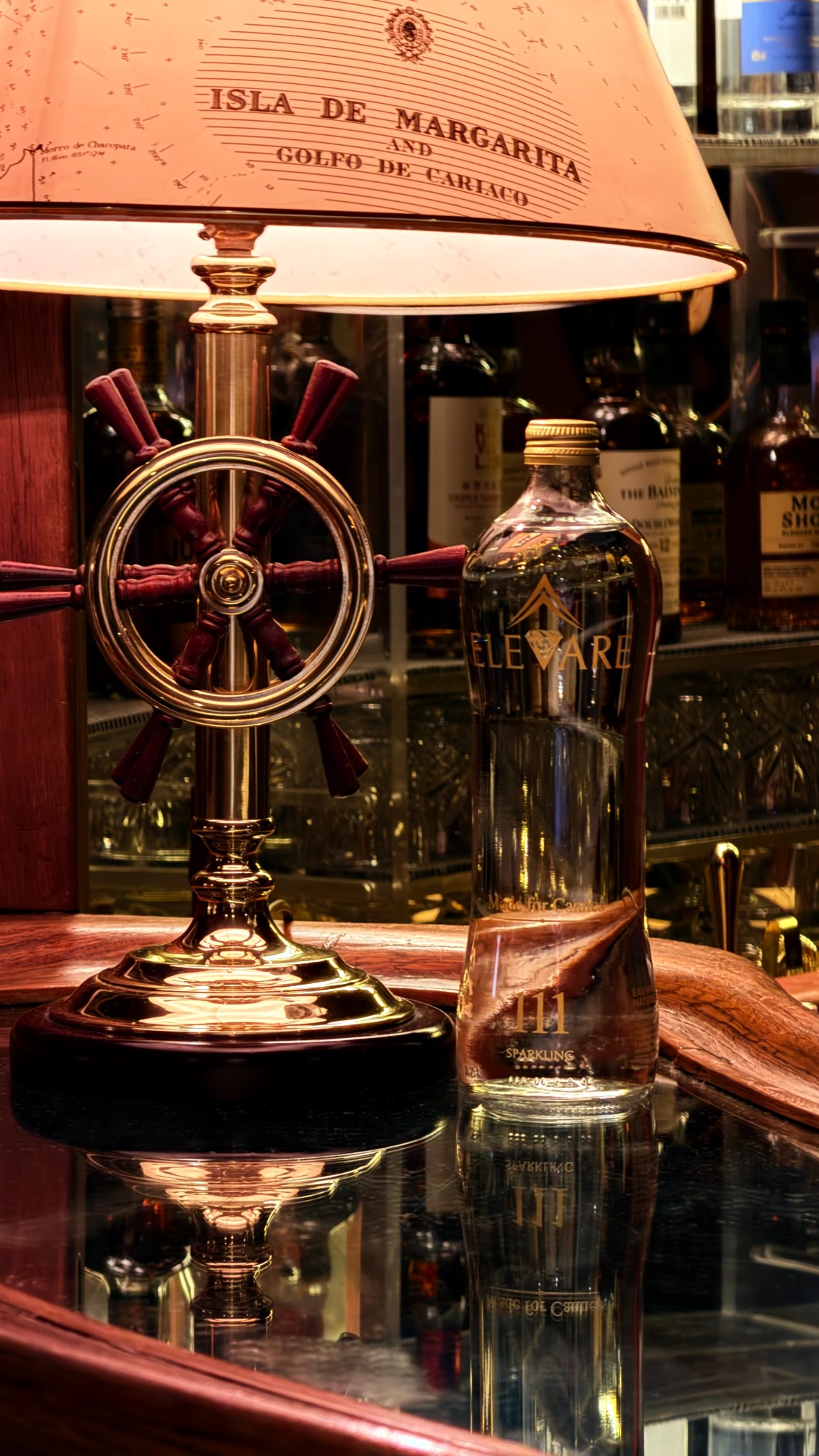 ELEVARE111 bottle beside the nautical lamp and wheel at Ari’s Bar aboard Christina O